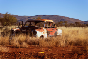 corroded vintage white and red sedan on brown grass