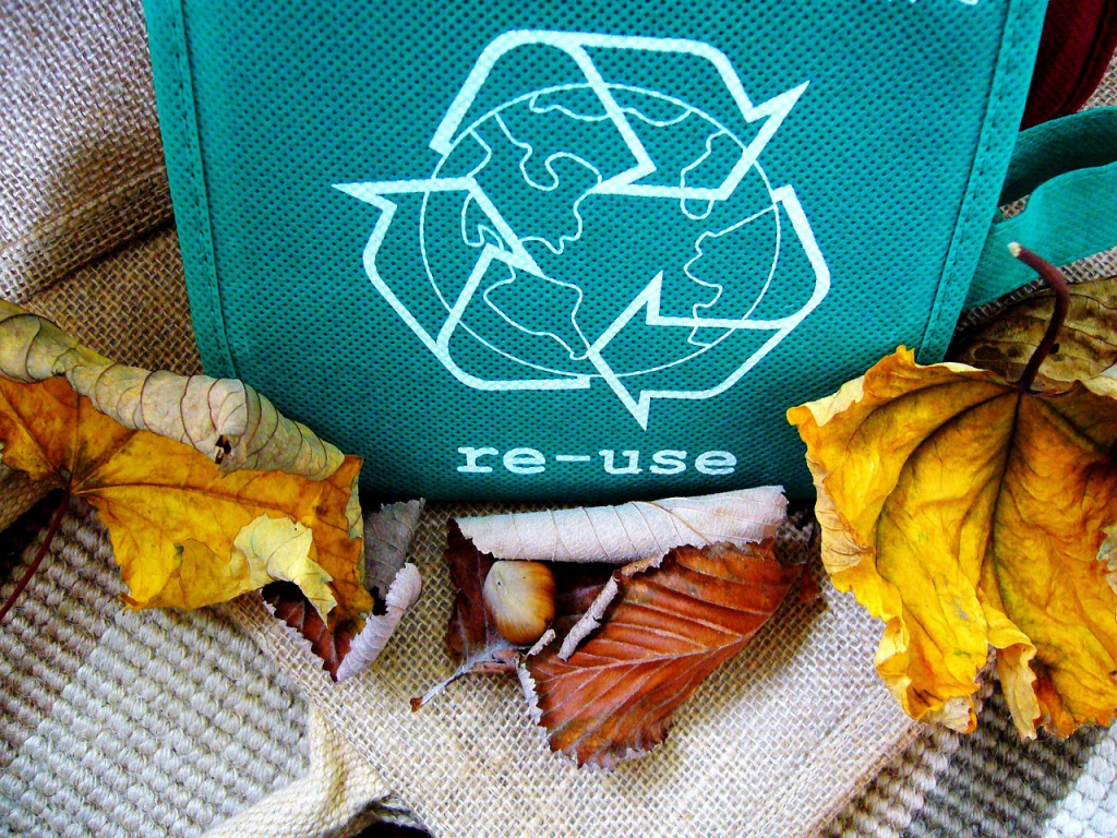 A green fabric symbolizing reduce, reuse, recycle surrounded by leaves.